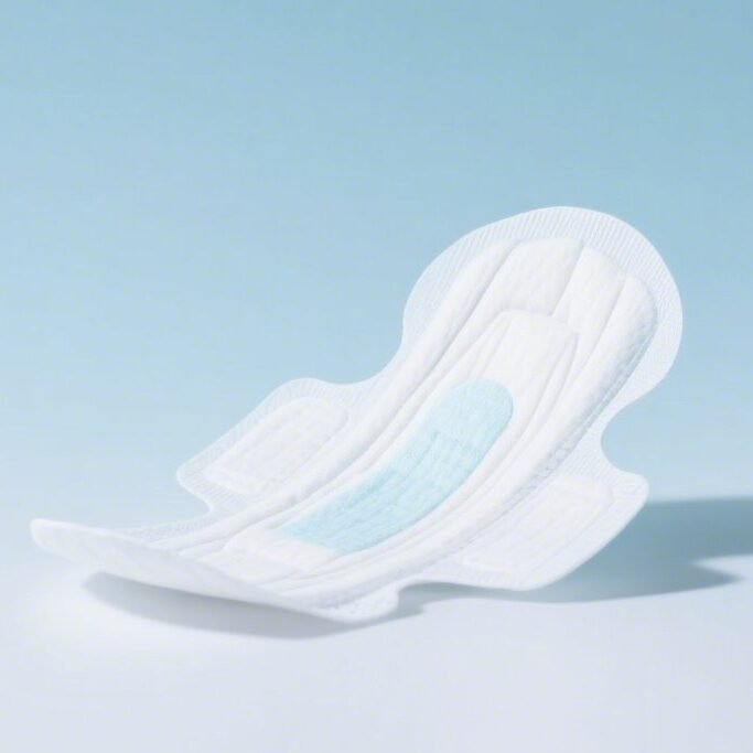 An image of a sanitary pad against a light blue backdrop, with a white, absorbent cotton design featuring protective wings on both sides and a blue liquid absorption area in the middle.