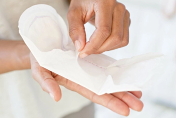 hand opening a disposable sanitary pad for feminine hygiene use